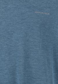 Kortärmad blå atletisk tröja tillverkad av texturerad tyg, med en subtil tryck av "ENDURANCE" på bröstet.