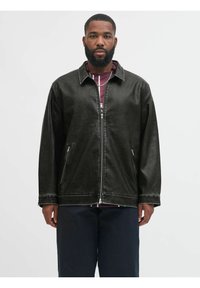 Musta tekonahkainen takki, jossa on vetoketjullinen etuosa, sivutaskut ja kauluksen näköinen kaulus. Korostaa kontrastivalkoista ommelta.