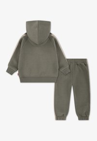 Sweatshirt à capuche vert olive et joggers assortis, avec des poignets élastiques et un style décontracté pour un confort optimal.