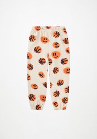Cremefarvede joggers med et mønster af orange og sorte smiley-ansigtter blandet med basketballer. Elastisk talje og tætsiddende manchetter.