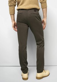 Donkerbruine slim-fit broek van katoen met een gladde textuur, met achterzakken en een leren logo op de tailleband.