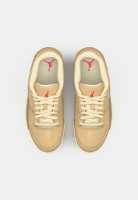 Baskets marron clair avec des accents beiges, dotées d'une tige en cuir lisse, de lacets crème et d'un logo rouge sur la languette et la semelle intérieure.