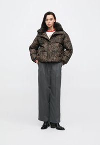 Puhasta jakna z leopardjim potiskom in krznenim ovratnikom, z zadrgo. Kombinirana z visokim pasom sivih hlač in gležnjarji.