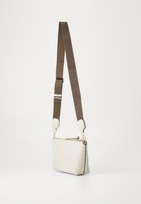 Biely kožený crossbody vak s obdĺžnikovým tvarom, hnedým nastaviteľným popruhom, zlatými kovovými doplnkami a prešívaním po stranách.