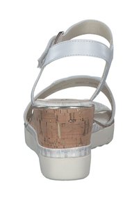 Witte kurken hak sandalen met verstelbare riem, een gladde bovenkant en een gestructureerd patroon op de zool. De hakhoogte is gemiddeld en ondersteunend.