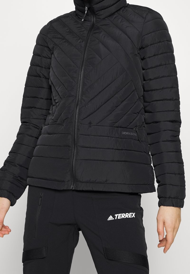 Svart puffjacka med hög krage, vertikal och diagonal quiltad design, med fickor med dragkedja och varumärkeslogotyp på vänster sida.