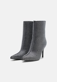 Sorte ankelstøvler prydet med sølvnitter, med spiss tå og stilettihæler, glatt tekstur og elegant design.