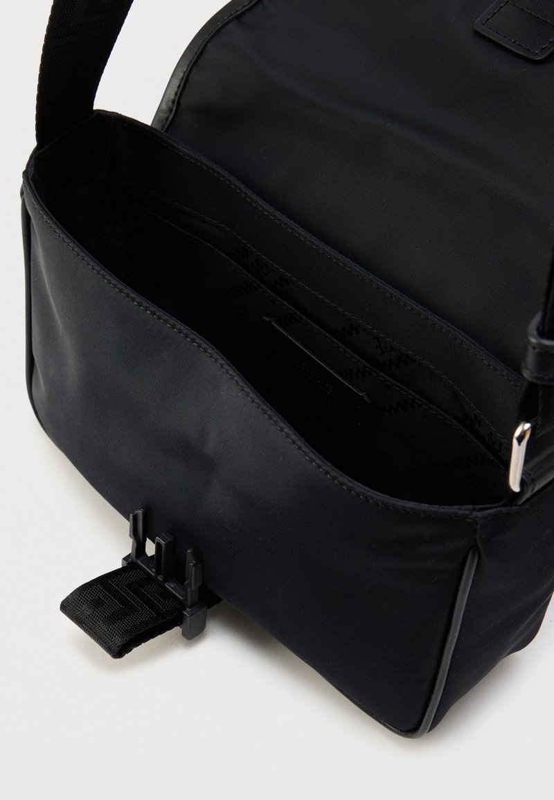 Schwarze Nylon-Umhängetasche mit glatter Oberfläche, verstellbarem Riemen und vorderer Schnallenverschluss. Das Innere verfügt über mehrere Fächer.