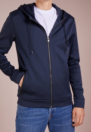 Sudadera con cremallera de color azul marino con un acabado texturizado, que cuenta con capucha y cordones, bolsillos laterales y puños y dobladillo acanalados.