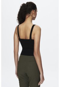 Zwarte nauwsluitende tanktop met brede bandjes, gecombineerd met textuur groene geruite broek. De top heeft een vierkante halslijn en een cropped pasvorm.