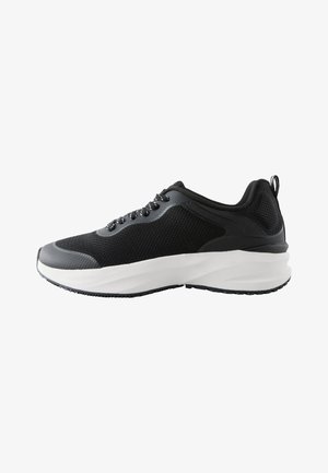 Sneaker sportiva nera e grigia con suola bianca spessa, tomaia a rete, allacciatura frontale e linguetta sul tallone, vista di profilo.
