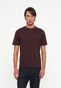 Bordeauxkleurig t-shirt met ronde hals, gemaakt van katoen, met korte mouwen en een ontspannen pasvorm. Eenvoudig ontwerp zonder patronen of versieringen.