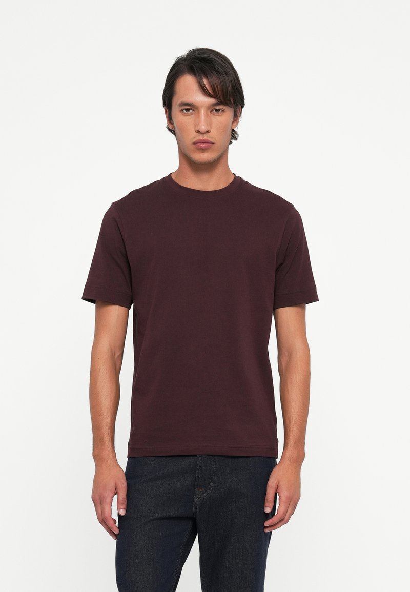 Bordeauxkleurig t-shirt met ronde hals, gemaakt van katoen, met korte mouwen en een ontspannen pasvorm. Eenvoudig ontwerp zonder patronen of versieringen.