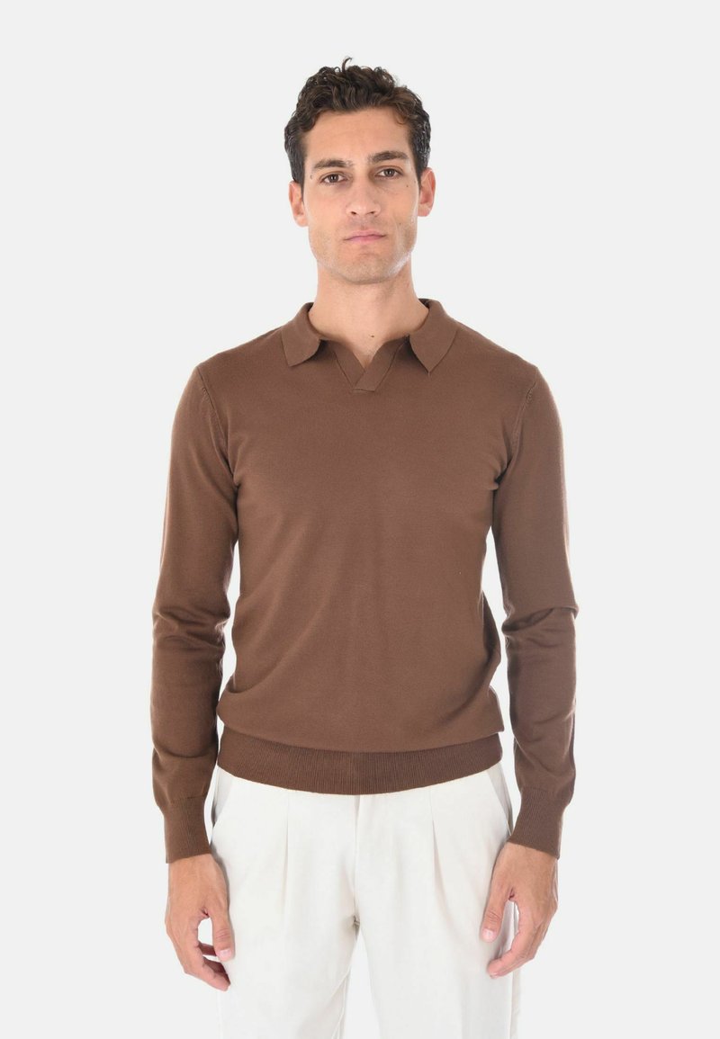 Maglione in maglia marrone con scollo a V e colletto corto. Presenta una vestibilità aderente e un orlo a coste. Abbinato a pantaloni color crema.