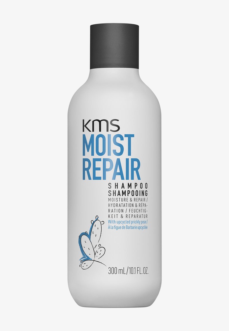 Flacon de shampooing blanc avec bouchon noir étiqueté "kms Moist Repair Shampoo" pour l'hydratation et la réparation, avec une illustration d'un papillon bleu.