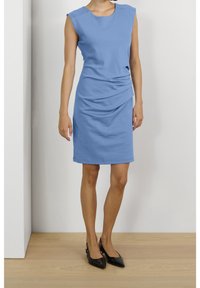 Modrá bezramenná šaty s kulatým výstřihem, skládáním v pase a slim fit, doplněné černými balerínami s špičatou špičkou.