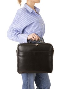 Borsa per laptop in pelle nera con texture liscia, chiusura a doppia cerniera e design semplice. Il modello la tiene accanto a una camicia a righe blu.