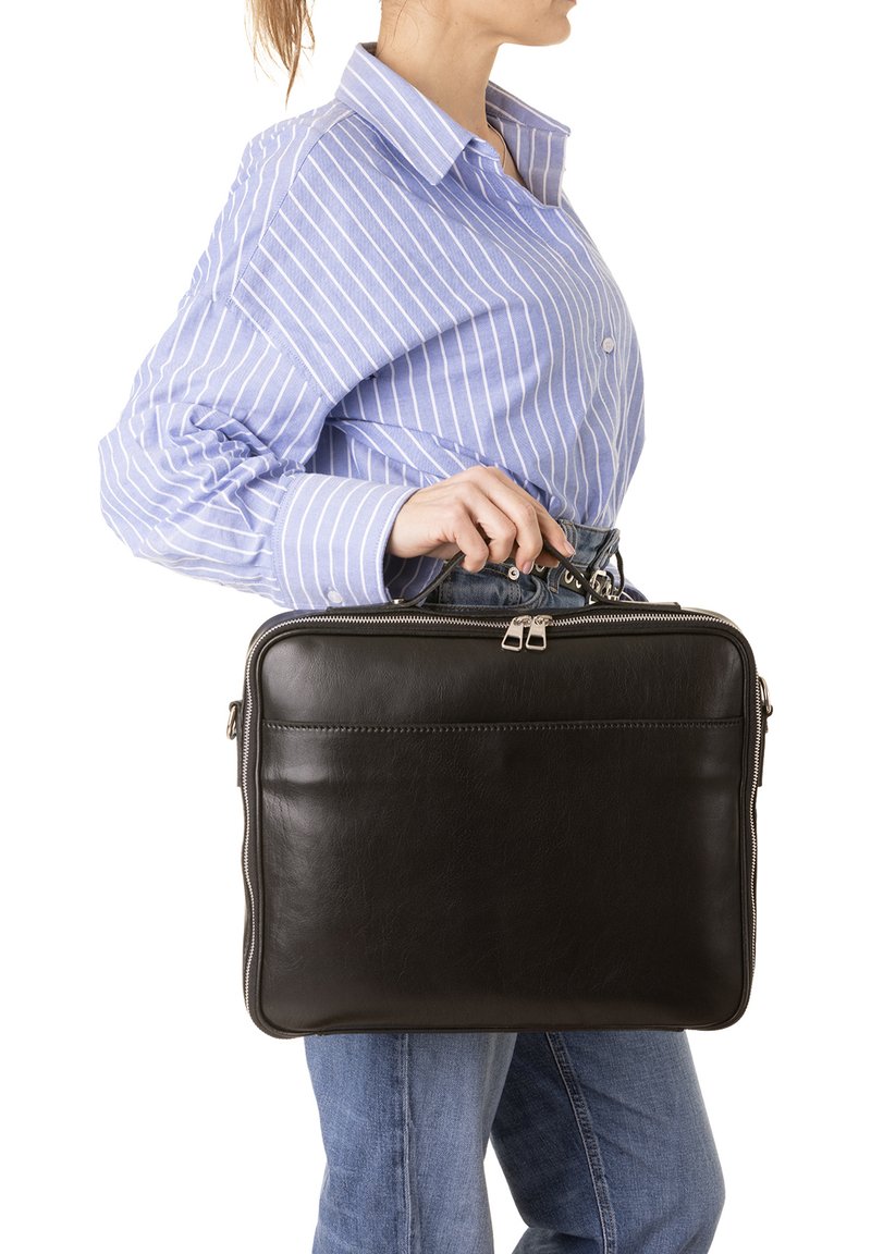 Borsa per laptop in pelle nera con texture liscia, chiusura a doppia cerniera e design semplice. Il modello la tiene accanto a una camicia a righe blu.