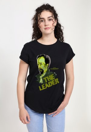 Schwarzes T-Shirt mit kurzen Ärmeln, das ein bedrucktes Grafikmotiv eines Mannes mit dunklen Haaren und Bart zeigt, mit dem Text "DER FÜHRER" in Gelb und grünen Akzenten.