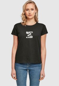 Sort bomulds T-shirt med rund hals og korteærmer, prydet med en hvid, uregelmæssig tekstgrafik, der siger "BREAK THE RULES."