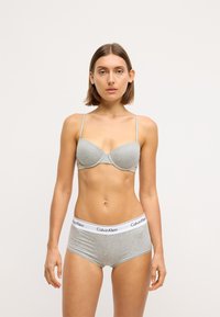 Šedá bavlnená podprsenka s tvarovanými košíčkami a tenkými ramienkami, spárovaná so šedými bavlnenými boxerkami s bielym pásom Calvin Klein.