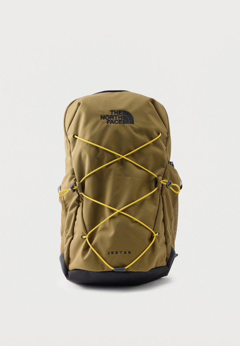 Σακίδιο πλάτης North Face Jester σε ελιά πράσινο με μαύρη βάση, κίτρινα ελαστικά κορδόνια μπροστά, πλαϊνές τσέπες από δίχτυ και κλείσιμο με φερμουάρ στην κορυφή.