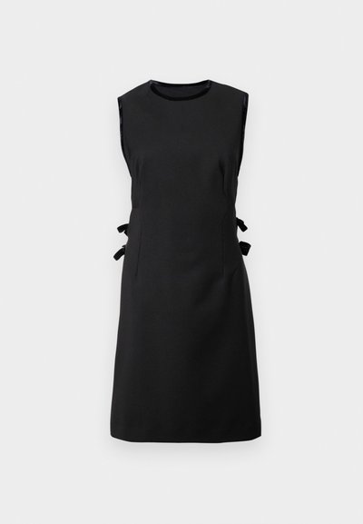 Vestido negro sin mangas de una tela suave, con lazos laterales, escote redondo y cintura ajustada, con una falda recta.