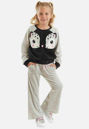 Grau und schwarz Plüsch Sweatshirt mit Tiergesicht-Design, kombiniert mit hellgrauen Jogginghosen. Die Schuhe sind silber mit rosa Akzenten.