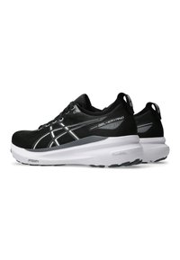 Zwarte hardloopschoenen met een bovenwerk van mesh en reflecterende accenten. Voorzien van een dikke witte tussenzool voor demping en een gestructureerde rubberen loopzool.