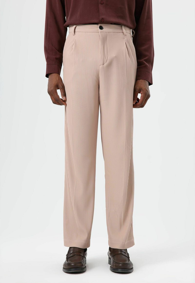 Beige plissébroek met een geribbelde textuur en een rechte pijp. Voorzien van steekzakken aan de zijkant en een knoopsluiting in de taille.