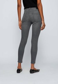 Grå skinny jeans med hög midja, som har bakfickor och en slät denimtextur. Kombinerat med svarta ballerinaskor och en enfärgad svart topp.