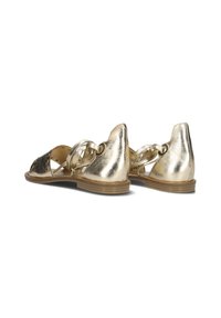 Metalen gouden sandalen met een strakke vormgeving, voorzien van twee ronde accenten en een combinatie van effen en gemusterde texturen. Platte zool, open achterkant.