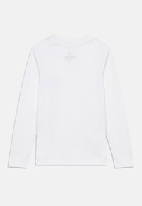 Λευκό βαμβακερό πουκάμισο με μακριά μανίκια, λαιμόκοψη σε σχήμα κυκλικού και μικρό, λεπτό λογότυπο στο πίσω μέρος κοντά στον λαιμό. Κλασική εφαρμογή και λεία υφή.