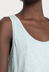 Lichtblauw tanktop gemaakt van zachte stof, met een ronde halslijn en brede armsgaten, met een relaxed pasvorm en een lichte textuur.