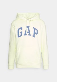 Capuchon sweatshirt in neon geel met een zachte textuur, voorzien van een blauw "GAP" logo, geribbelde manchetten en een kangoeroezak aan de voorkant.