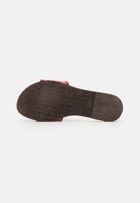 Gummisula med texturerat grepp, prydd med färgglada tygremmar i röd, gul och rosa. Flat design med ergonomisk form.