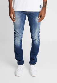 Bleka blå denimjeans med rak passform, med ljusare toner på låren, kombinerade med vita sneakers.