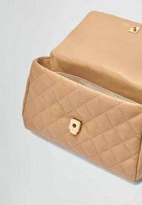 Beige tikandidega nahk-kott kullast ruudukujulise lukuga. Esipaneelil on teemantmuster ja sujuv, ümar ülaosa.