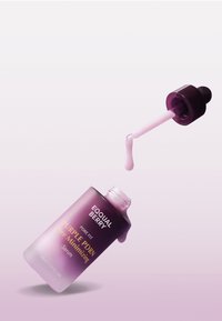 Fioletowa szklana butelka w gradientowym kolorze z pipetą, zawierająca jasnoróżowy serum. Etykieta brzmi "EQUAL BERRY PURPLE PDRN Serum minimalizujące pory."