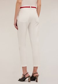 Witte broek met een aangesloten taille en een rode riem. Bevat twee achterzakken en cropped pijpen. Zwarte en grijze hoge hakken ronden de look af.