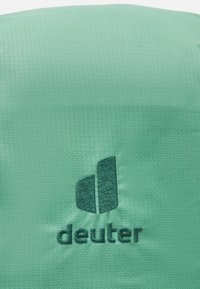 Green fabric with a textured finish, featuring an embroidered dark green logo and lettering "deuter" at the bottom.