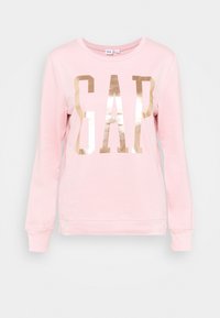 Ljusrosa långärmad sweatshirt med stor skinande guldig "GAP"-logotyp över framsidan, rundad hals och ribbade ärmslut och fåll.