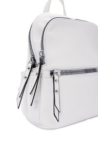 Zaino in pelle bianca con superficie texturizzata, tasche a doppia zip, dettagli neri e accessori lucidi. Forma compatta e arrotondata.