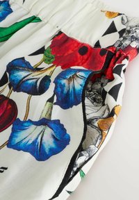 Bloempatroon stof met levendige blauwe, rode en groene ontwerpen. Kenmerkt een geplooide tailleband en contrasterende zwart-witte accenten.