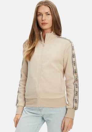 Felpa beige con zip, dettagli logo neri sulle maniche, polsini e orlo a costine, realizzata in tessuto morbido. Presenta collo alto e tasche.