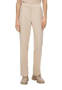 Pantalon beige ajusté avec une coupe droite. Tissu lisse avec passants de ceinture et plis à l'avant. Associé à des mocassins beiges avec des accents dorés.