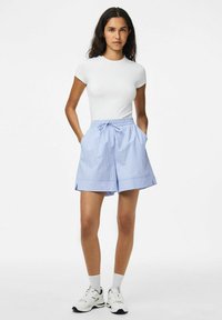 Zili un balti svītraini šorti ar elastīgu jostasvietu un auklu. Ar sānu kabatām un brīvu piegriezumu. Valkāti kopā ar baltu T-kreklu un sneakers.