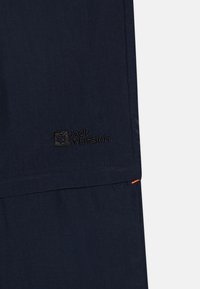 TM tumši zili šorti, kuri izgatavoti no viegla auduma, ar izšūtu Jack Wolfskin logotipu un nelielu oranžu šuvju detaļu apakšējā malā.