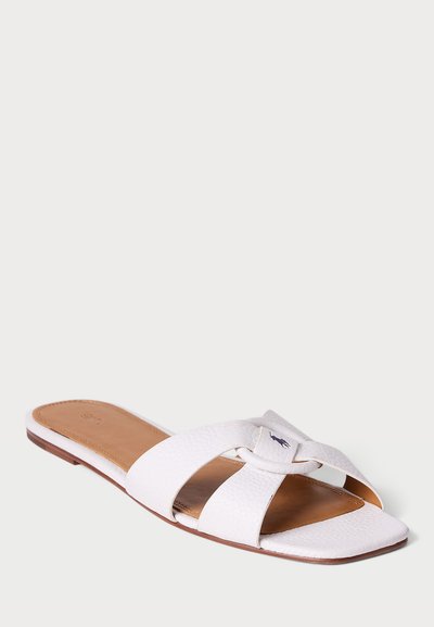 Sandal de slide em couro branco com design de tiras cruzadas, apresentando um acabamento texturizado e um pequeno logotipo em uma das tiras. Sola plana.