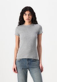 Tricou gri cu mânecă scurtă, cu o textură ribbed și un decolteu rotund, asortat cu blugi din denim de culoare albastră deschisă. Design simplu și ajustat.